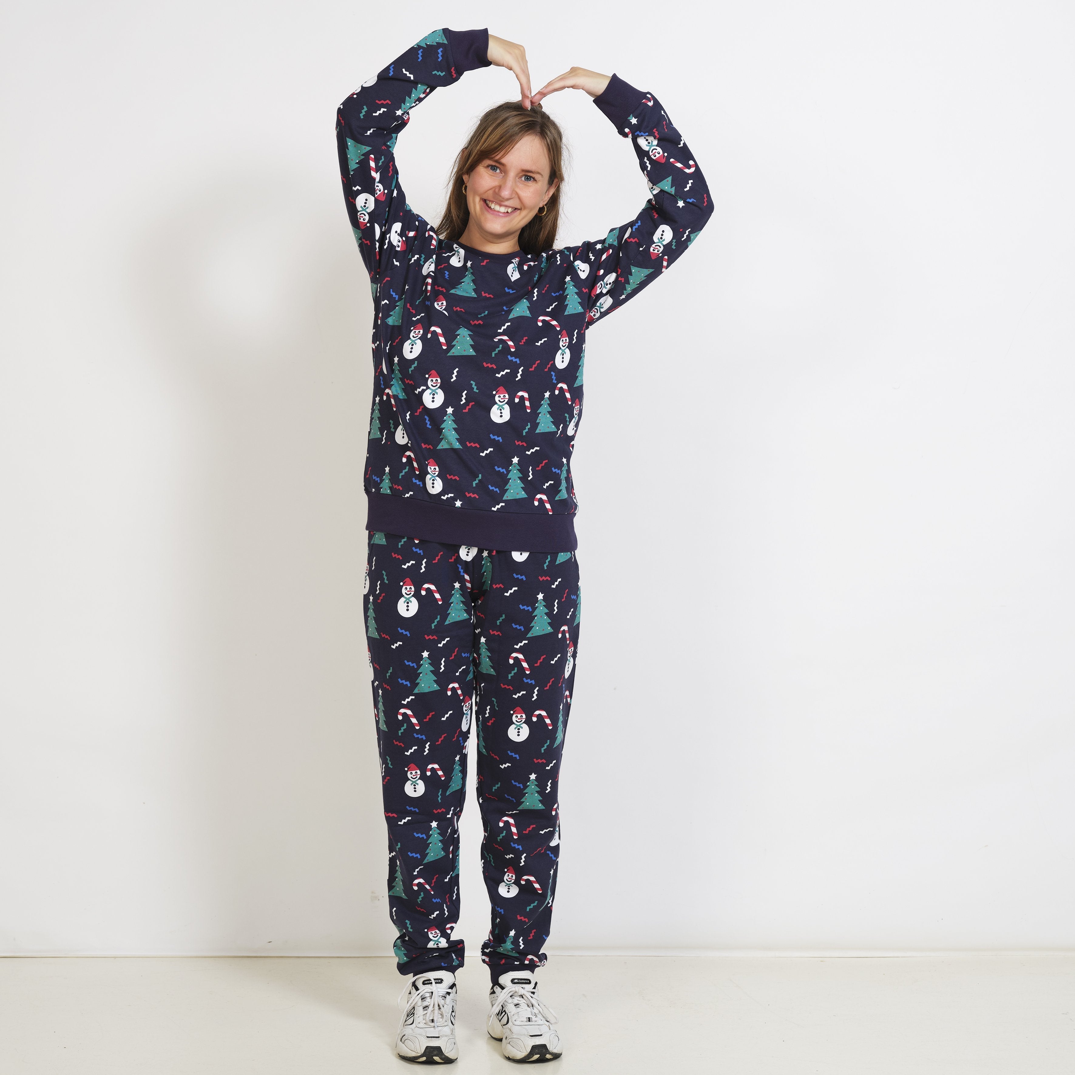 Ein Paar, das einen dunkelblauen Weihnachtspulli mit Weihnachtsbäumen und Schneemännern trägt.
